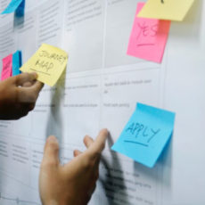 Decorative photo of hands arranging post-it notes