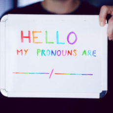 Photo of person holding up sign with text "Hello, my pronouns are: __/__"