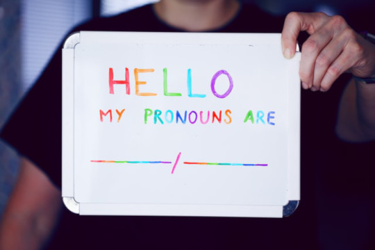 Photo of person holding up sign with text "Hello, my pronouns are: __/__"
