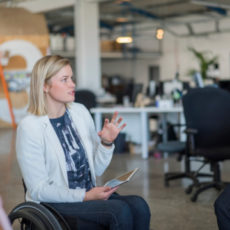 Decorative photo of person in wheelchair talking to colleague