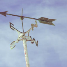 Decorative photo of compass against sky