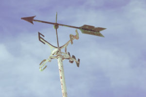 Decorative photo of compass against sky