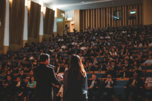 Decorative photo of people on stage at a conference