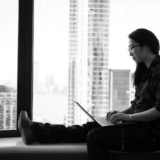 Person sitting on window sill with laptop