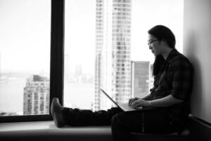 Person sitting on window sill with laptop