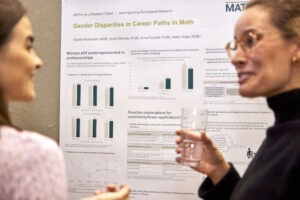two people in a discussion at the poster session by math+