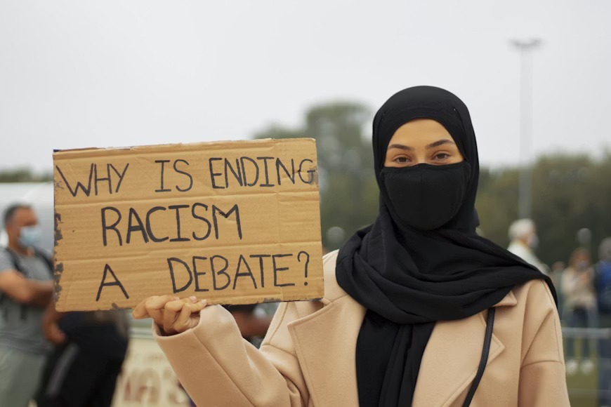 Decorative photo of person holding sign "Why is ending Racism a debate?"