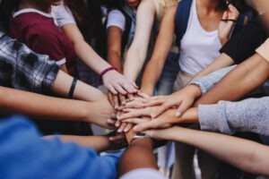 Multicultural teenagers putting their hands together in a huddle. Group of unrecognizable young people expressing their unity and teamwork
