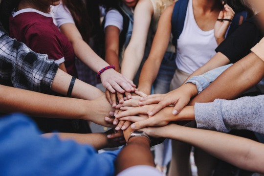 Multicultural teenagers putting their hands together in a huddle. Group of unrecognizable young people expressing their unity and teamwork