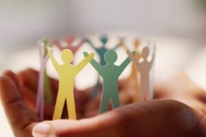 decorative photo of person holding a circle of colorful cut-outs of people holding hands